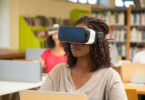 A young girl wears a virtual reality headset in a classroom.