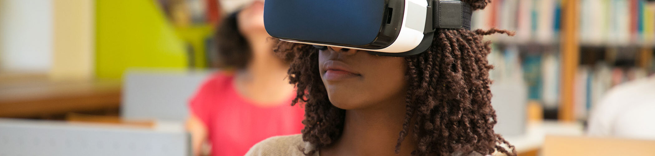 A young girl wears a virtual reality headset in a classroom.