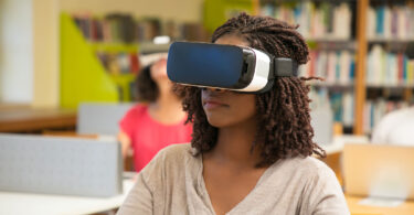 A young girl wears a virtual reality headset in a classroom.