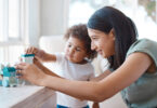 A mother plays with her child in a sunlit room.