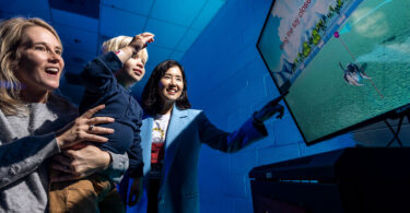 A woman shows her son how to use the virtual fitness buddy mixed reality game that encourages children to be physically active.