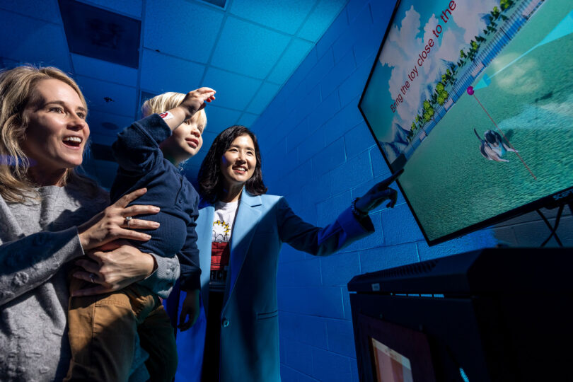 A woman shows her son how to use the virtual fitness buddy mixed reality game that encourages children to be physically active.