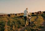 A woman walks on their family's farm with her small child.