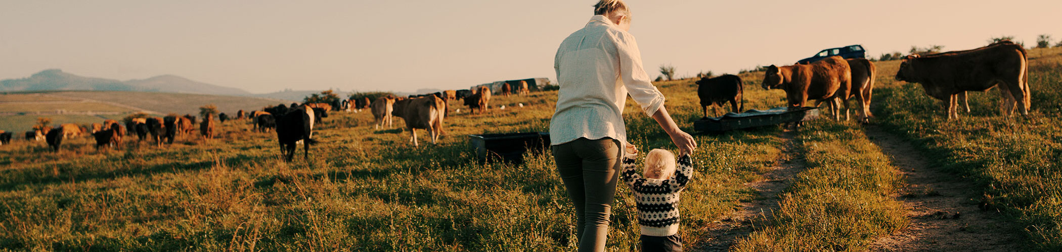 A woman walks on their family's farm with her small child.