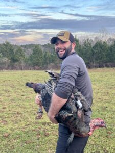 UGA professor holds turkey in a green field