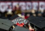 Detail of a decorated mortarboard that says "glory, glory" worn by a student during the 2023 Fall Graduate Commencement ceremony.