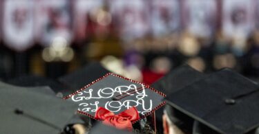 Detail of a decorated mortarboard that says "glory, glory" worn by a student during the 2023 Fall Graduate Commencement ceremony.