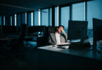 A smartly-dressed businessman is resting in his office in front of his computer. He is tired and wants to go home. His face is not recognizable. Low-key lighting. Horizontal night-time indoor photo. (Getty Images)