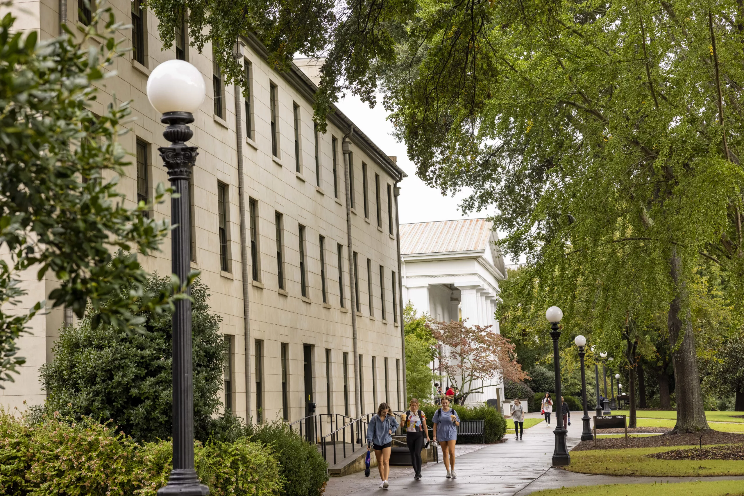 View of New College with students walking on the North Campus sidewalk after an afternoon rain shower. (Dorothy Kozlowski/UGA)