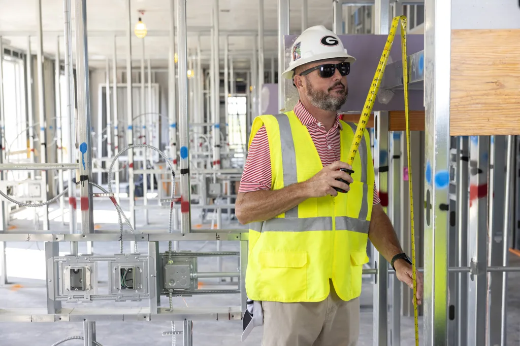 A man uses a measuring tape at a construction site.