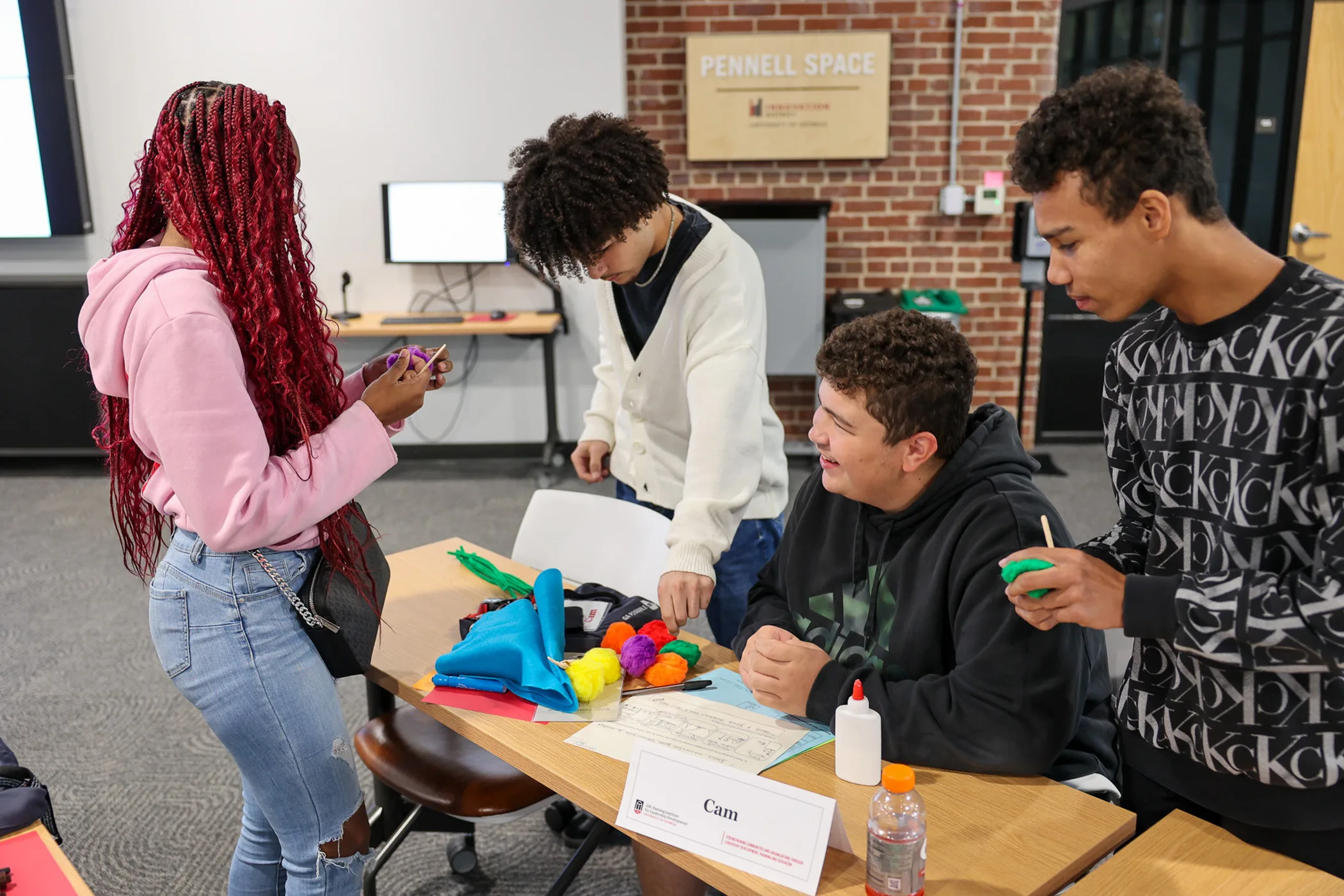 Four students collaborate on a colorful craft project with fabric and materials.