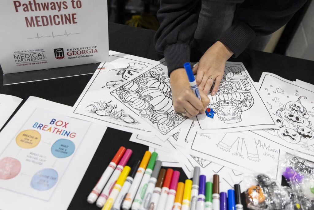 A participant colors on a printed page with a marker at the Normaltown Community Health Fair at George Hall on the Health Sciences Campus.