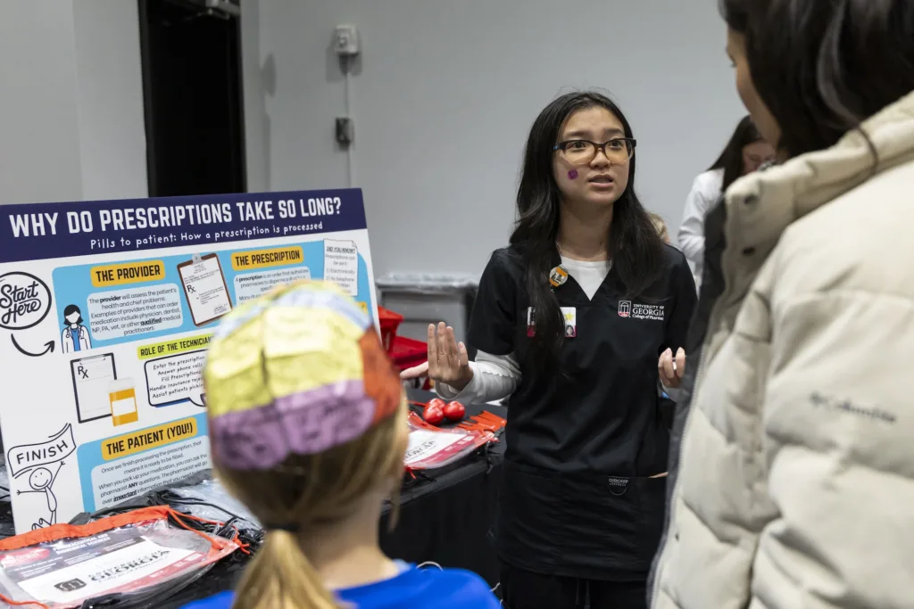Elizabeth Tran, Pharm.D. and MPH Candidate, speaks to community members in front of a visual display about the prescription process.