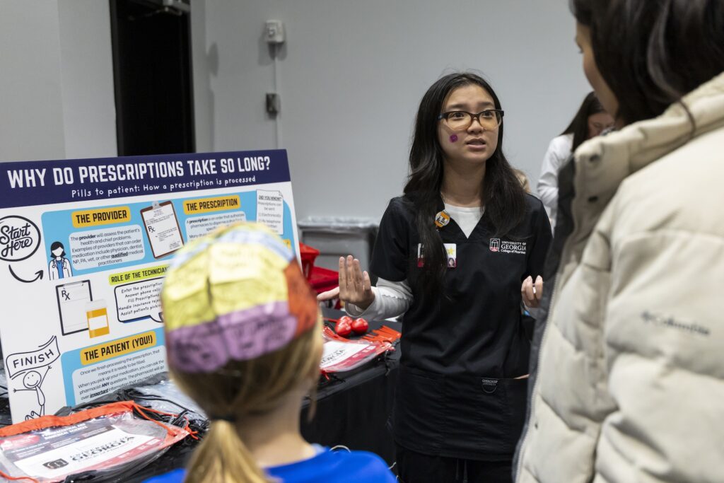 Elizabeth Tran, Pharm.D. and MPH Candidate, speaks to community members in front of a visual display about the prescription process.