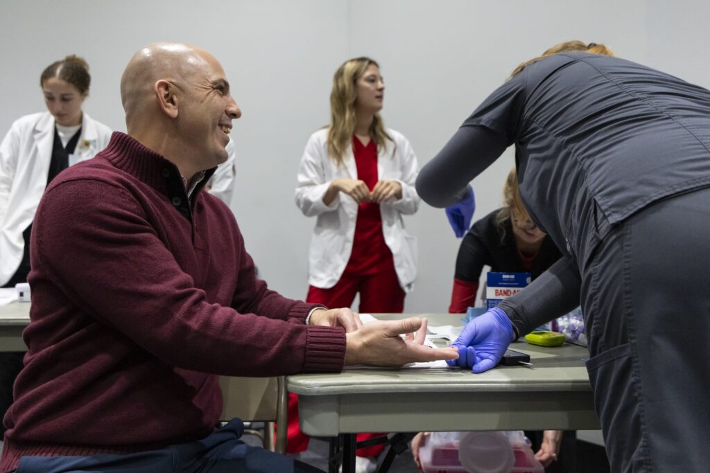 Jason Payton, Community Engagement Professional in the AU/UGA Medical Partnership, has his blood sugar levels checked during the Normaltown Community Health Fair.