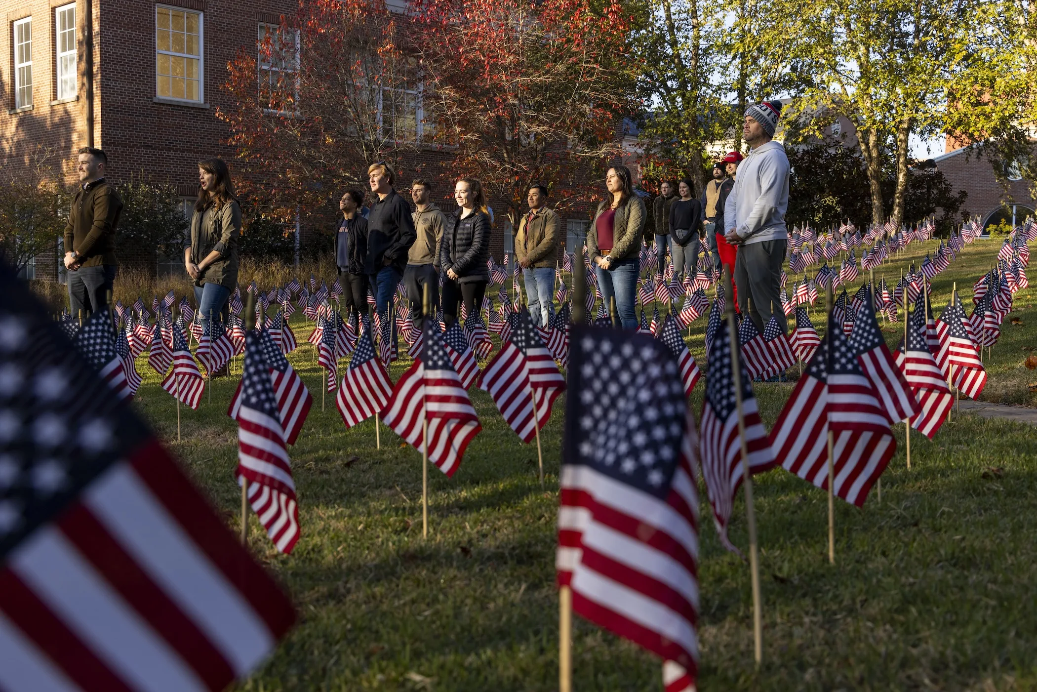 Student veterans pose for a photo in the middle of many American flags in the Memorial Garden outside the Miller Learning Center.