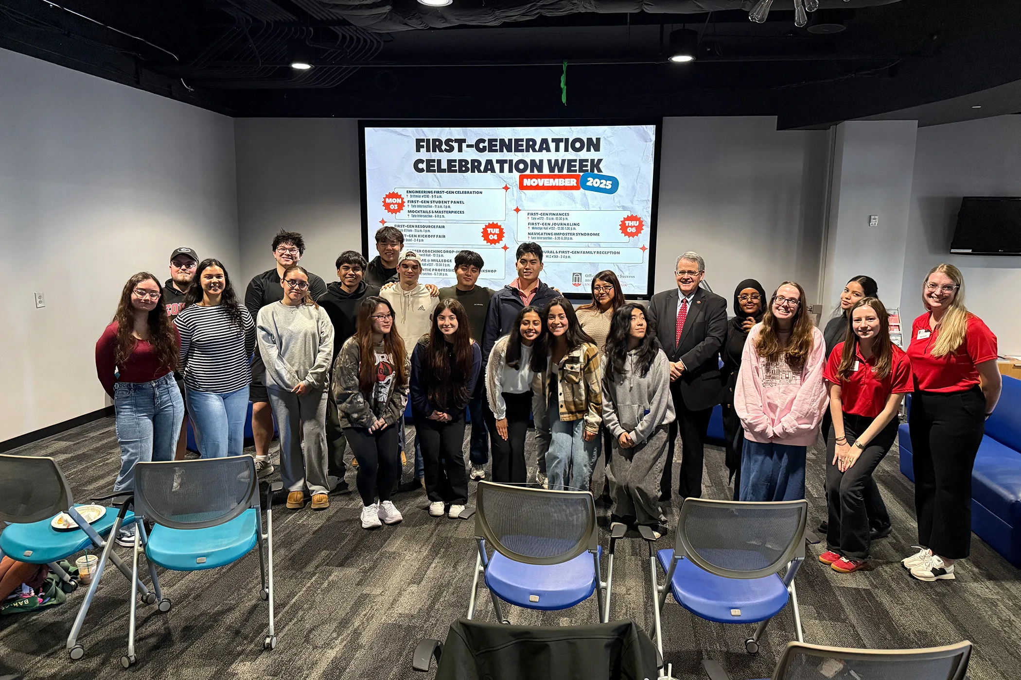 Students and UGA President Jere W. Morehead pose together in front of a First-Generation Celebration Week display.
