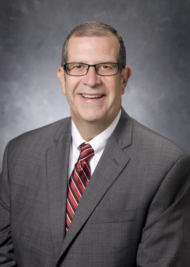 Headshot of a man wearing a suit and tie.