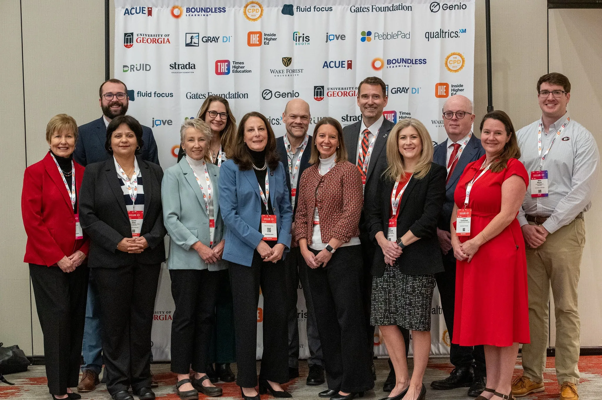 A large group of people stand in front of a backdrop at a conference.