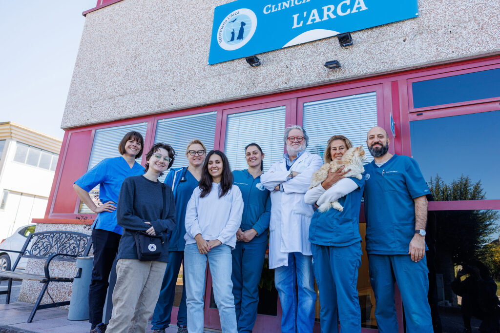 Student stands outside clinic entrance with veterinary staff, one of whom is holding a fluffy dog.