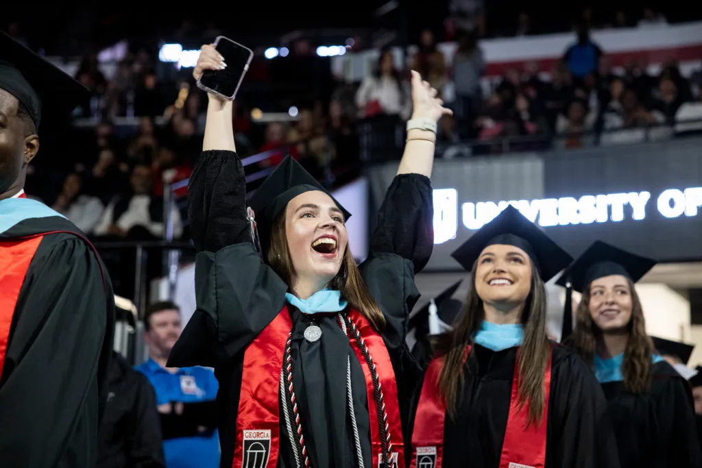 Graduates celebrate as they walk to their seats at the start of the fall graduate Commencement ceremony. (Billy Schuerman/UGA)