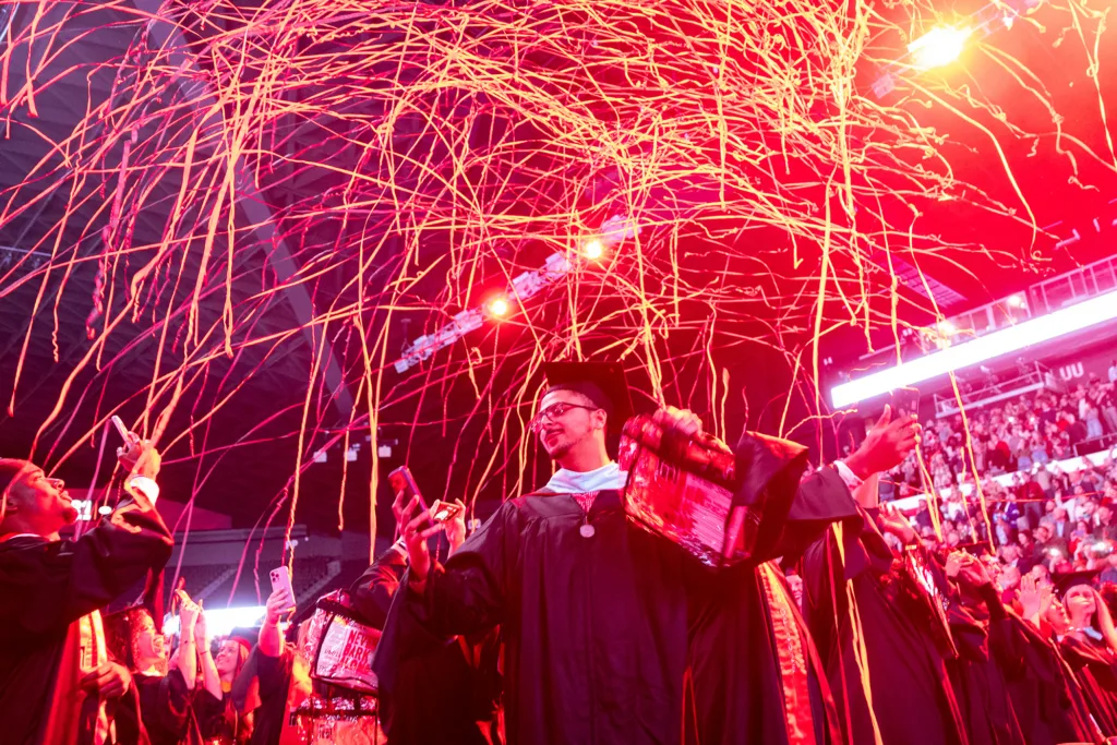 Streamers fly as graduates celebrate at the fall graduate Commencement ceremony at Stegeman Coliseum.