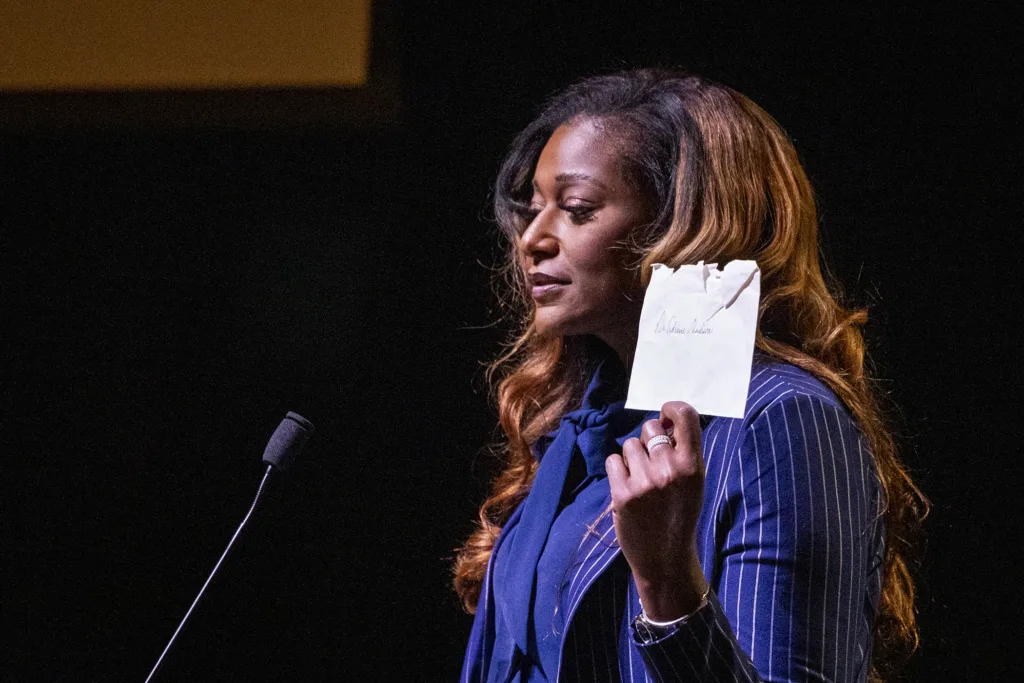 A woman stands at a podium giving a talk holding a letter.