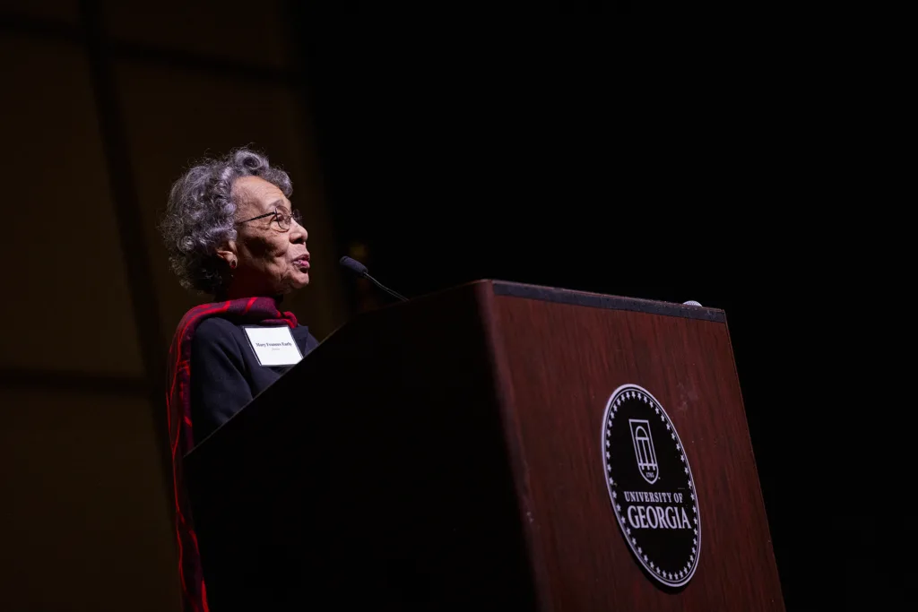 A woman speaks to a crowd from a podium.