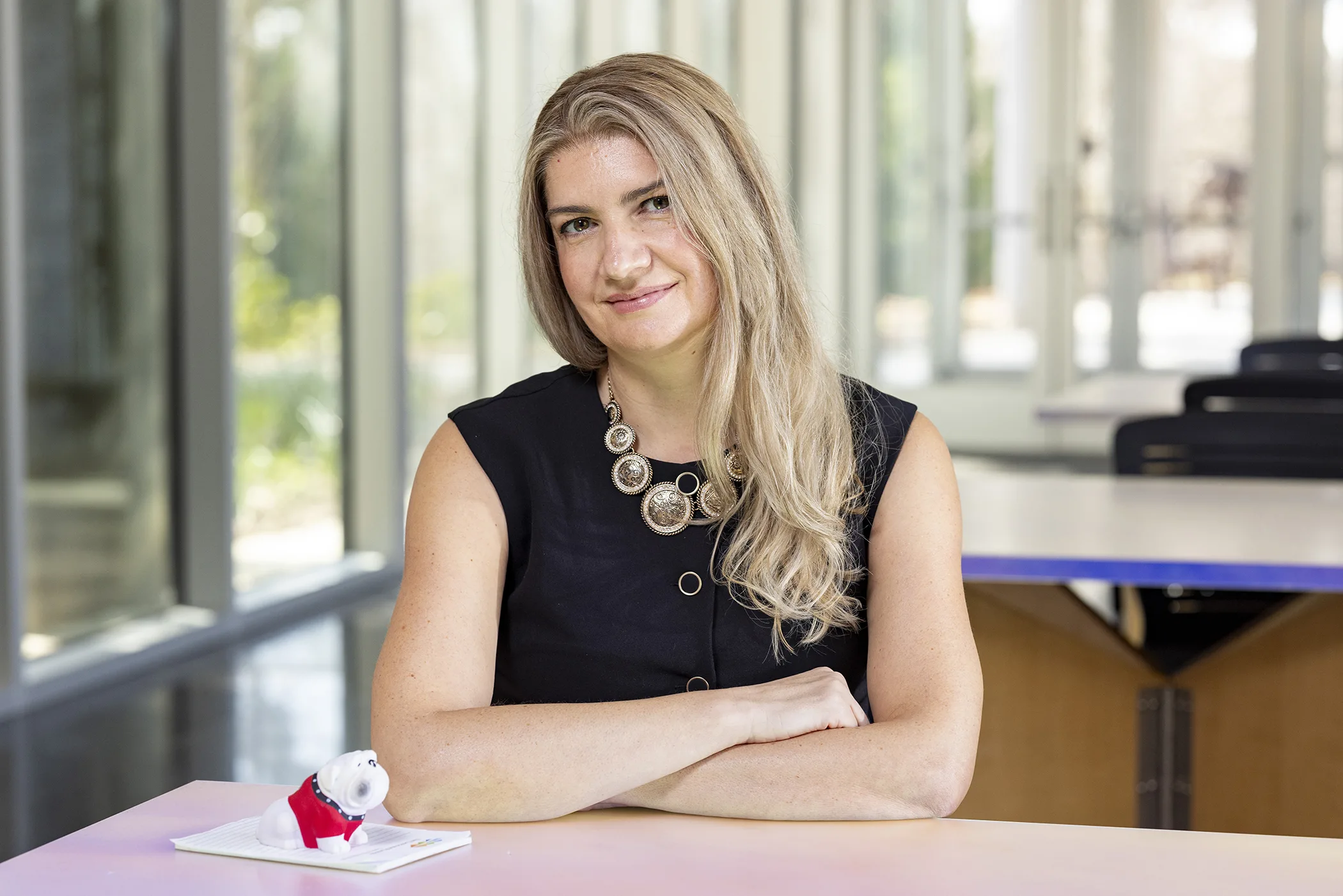A woman poses at a table in a classroom