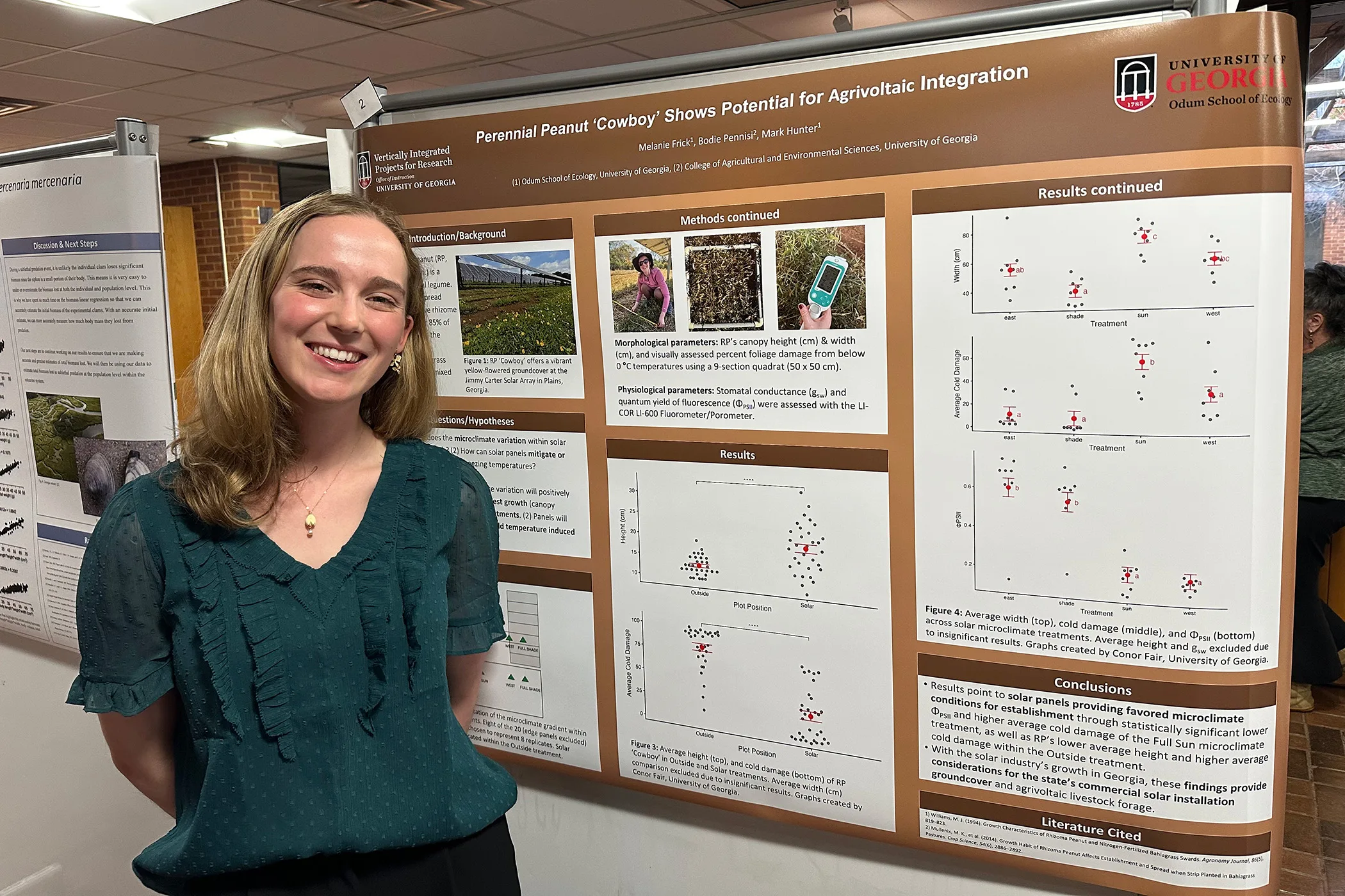 Melanie Frick stands beside a large research poster filled with charts and images during a poster session inside an academic building.