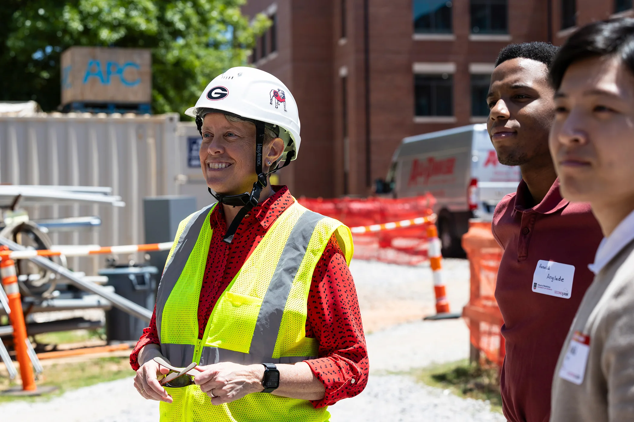 Shelley Nuss, wearing a hard hat and safety vest, stands with admitted students at a construction site.