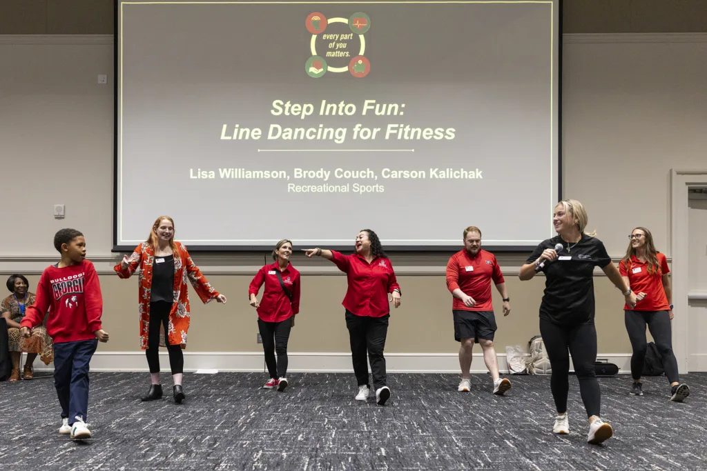A group teaches line dancing from the front of a large room