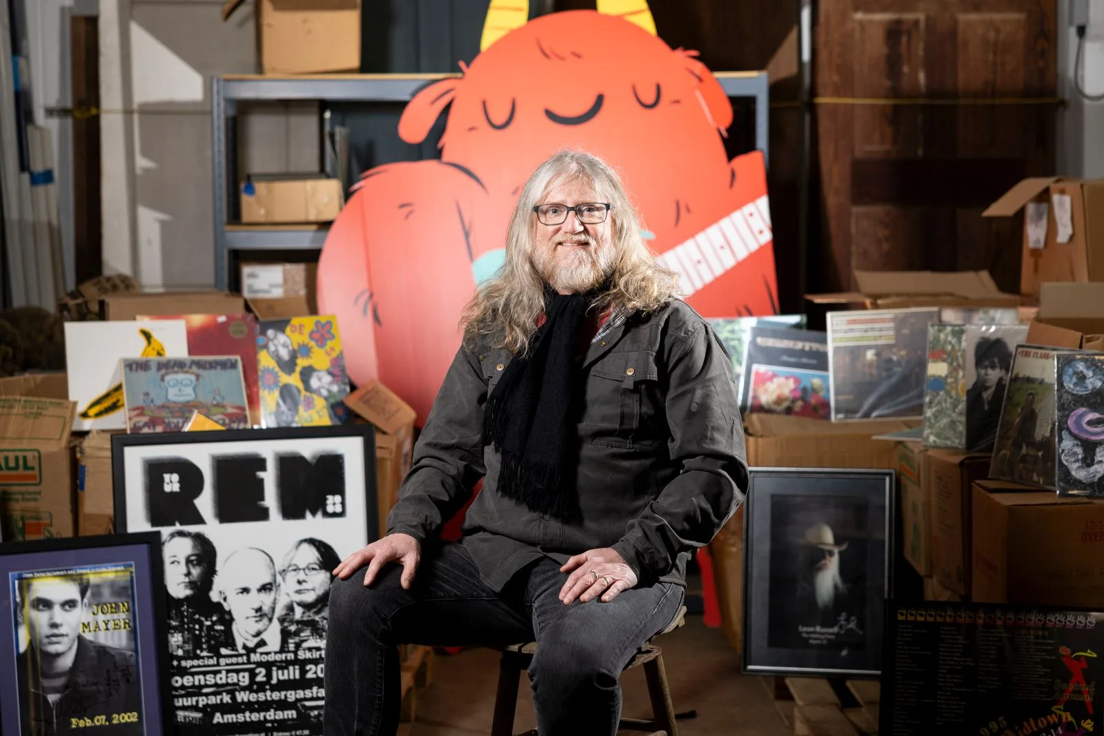 Troy Aubrey sits in a chair surrounded by music memorabilia.