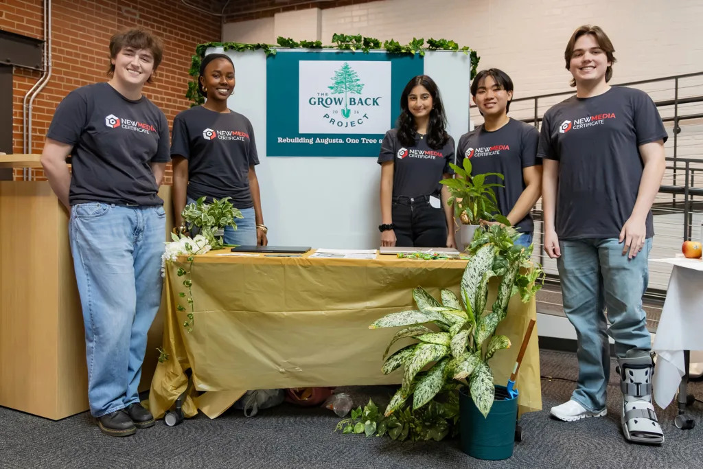 Five students stand near a decorated display for the Grow Back Project.