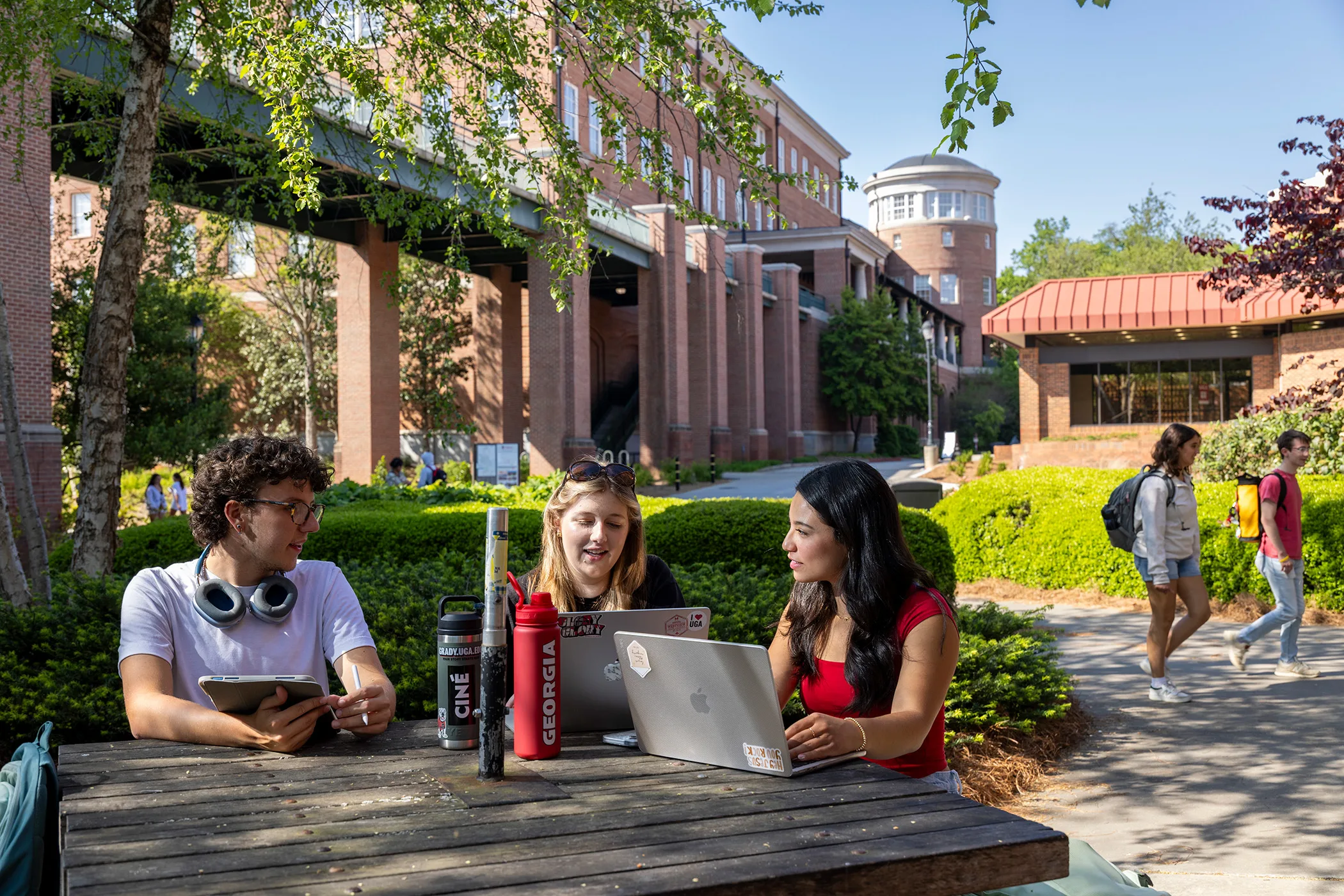 UGA students interact at an outdoor table with the Miller Learning Center in the background.