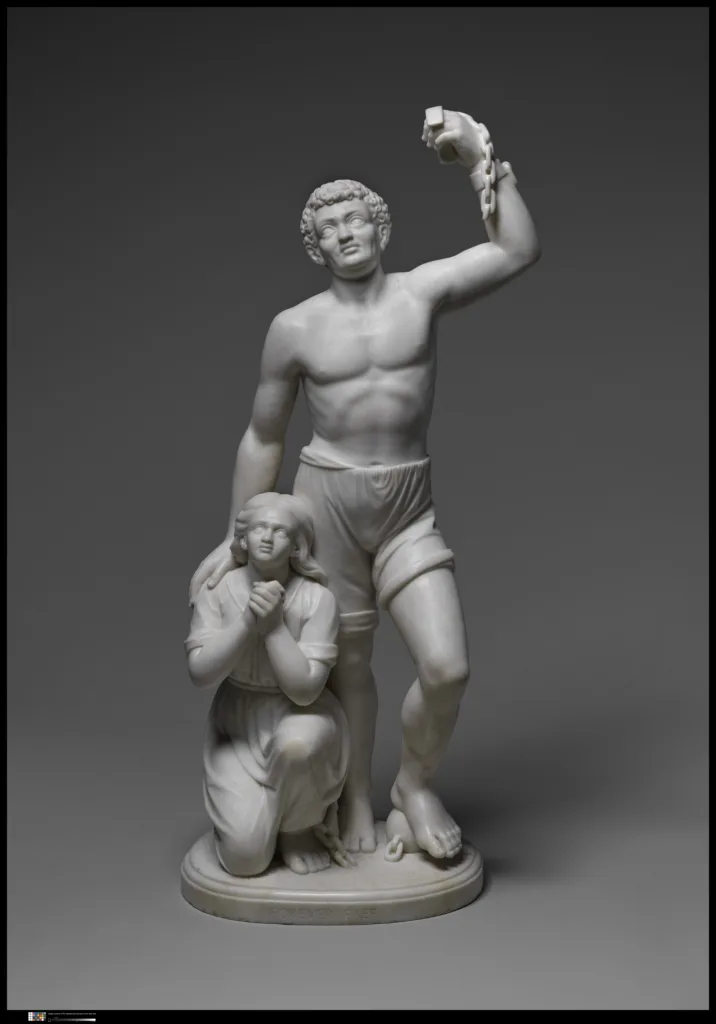 A marble sculpture by Edmonia Lewis, depicting a standing man raising a broken shackle above his head beside a kneeling woman with clasped hands.