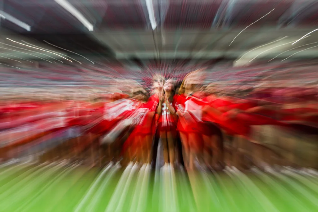 An extremely blurry image of people in red clothing on a green field.