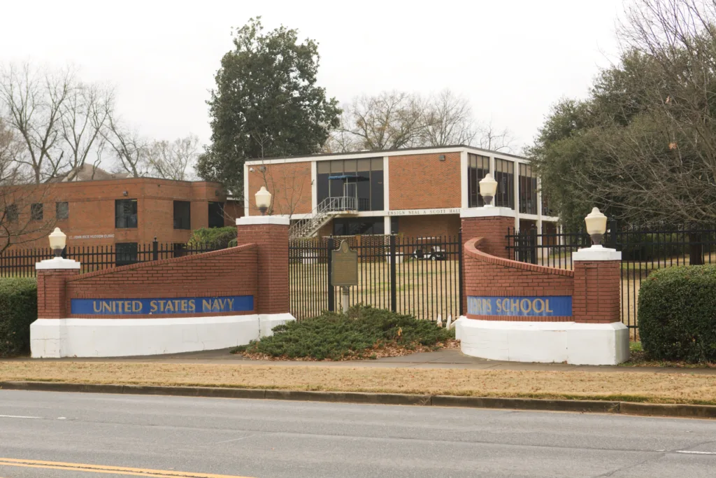 A metal gate in front of several brown, academic buildings.