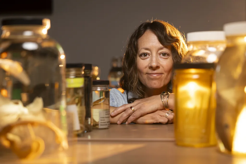 A woman peeks through a row of specimen jars lined up in front of her