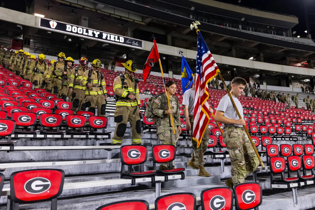 Firefighters in full turnout gear and ROTC cadets carrying flags descend the stairs of Sanford Stadium during a 9/11 memorial stair climb.