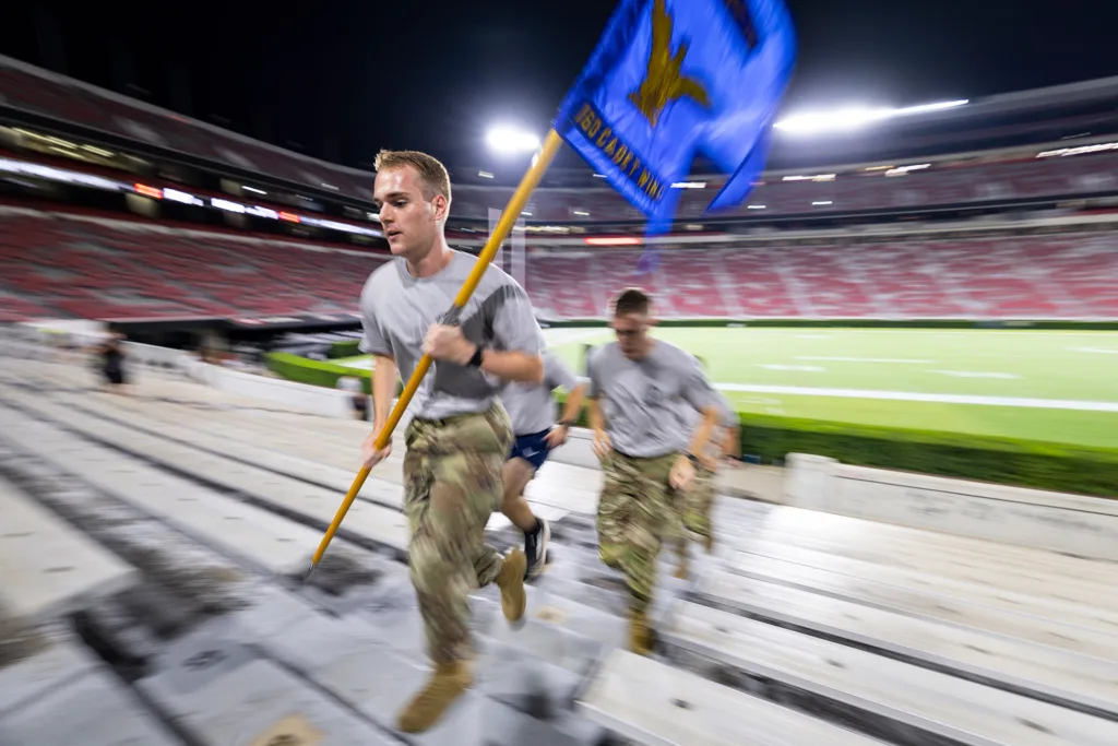 A participant holding a blue flag climbs the stadium steps at Sanford Stadium during a memorial stair climb.